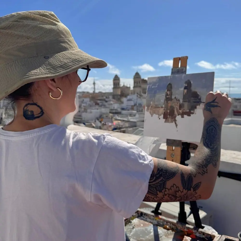 An artist participating in the Rencontres Delacroix paints the rooftops of Cádiz, with the cathedral in the background